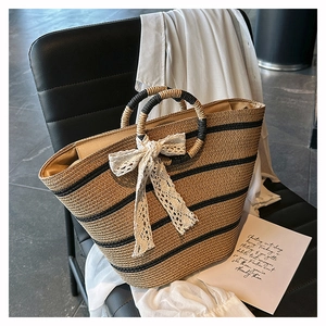 Detail of woven straw tote bag with black stripes and elegant white lace bow decoration