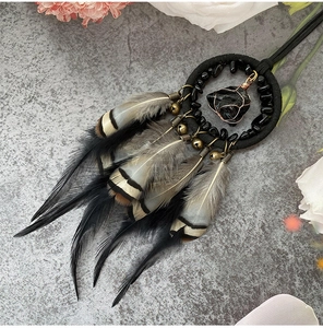 Detail of dreamcatcher pendant with black feathers, obsidian stone, and copper bells