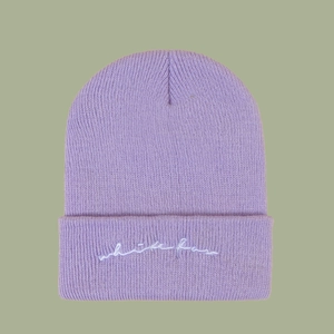 Macro detail of lavender knit beanie featuring white fan embroidery on ribbed cuff