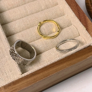 Detailed top view of gold and silver lava texture rings on beige velvet jewelry box lining