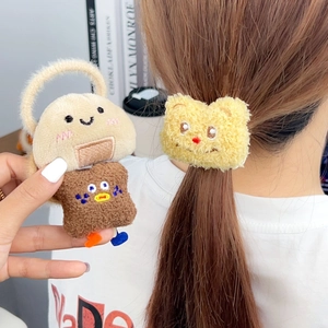 Detail showing two plush cartoon rice ball and bear hair ties worn on a bun