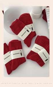 Detailed macro view of red knitted cotton socks with thick cable texture and paper labels