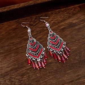 Detailed shot of retro silver earrings with red rhinestones and fringe on wood texture