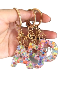 Three transparent resin initial keychains A, B, C with colorful heart sequins and gold hardware