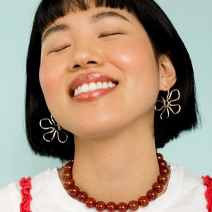 Elegant hollow floral stainless steel earrings paired with a beaded necklace on a model