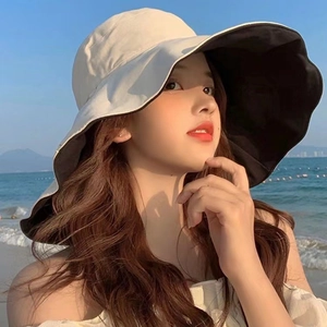 Detail of reversible sun hat showing the beige exterior and black lining at the beach