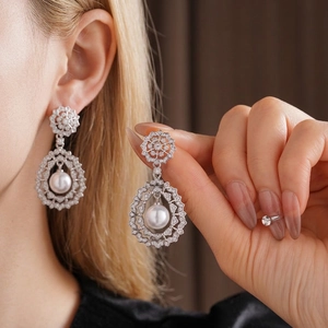 Vintage silver-tone pearl drop earrings featuring intricate crystal hollow design