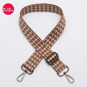 Detail of adjustable wide woven bag strap with brown houndstooth pattern and gunmetal hooks