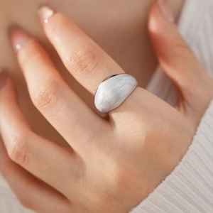 Close-up of a silver-toned organic fluid shape ring with white enamel finish
