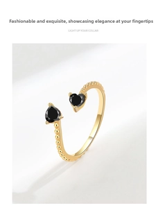 Close-up of golden bubble ring featuring dual heart-shaped black stones on open band