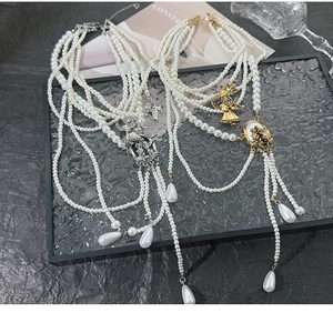 Flat lay of vintage multi-layer pearl necklaces with queen pendants and metal tassels