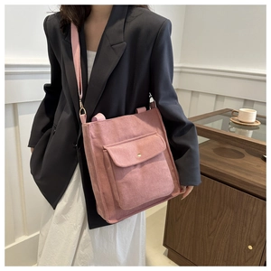 Detail of pink corduroy tote bag featuring front flap pocket and adjustable shoulder strap