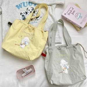 Detail of embroidered canvas tote bags with drawstring closure and cartoon sheep pattern