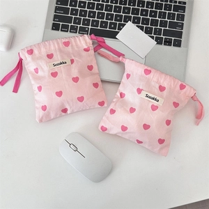 Close-up of pink canvas drawstring pouches with heart patterns for digital accessories