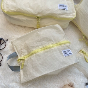 Detail view of yellow travel storage bags with plaid texture and dual zippers on white rug