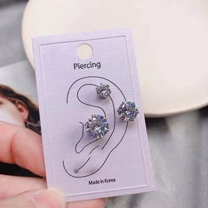 Close-up of three sparkling zircon magnetic earrings held on a display card for men and women