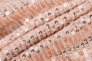 Macro de paillettes or rose sur tissu en maille montrant la texture et les détails