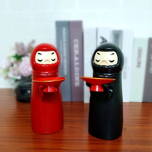 Detail of No Face Kaonashi money boxes in red and black colors with serving trays