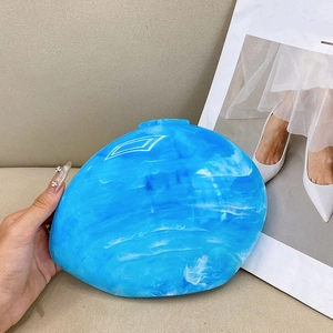 Close-up of blue marble acrylic clutch with smooth pebble shape held by hand