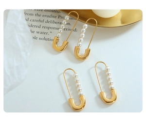 Macro detail of gold U-shaped paperclip earrings with five pearls in an elegant setting