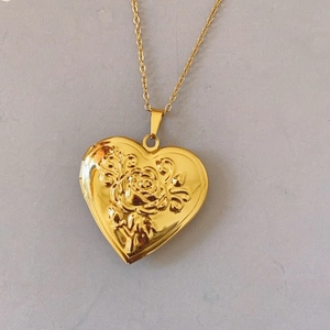 Detailed view of golden heart locket necklace with vintage rose relief pattern