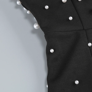 Détail de perles artificielles blanches brodées sur le tissu noir d'une robe de soirée