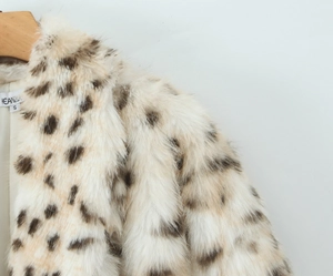 Détail de la texture d'un manteau en fausse fourrure léopard sur un cintre en bois