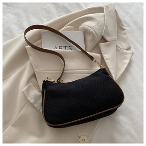 Detailed close-up of woven black shoulder bag with brown leather trim and golden hardware