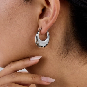 Polished silver titanium steel oval hoop earrings worn by a woman for a minimalist look