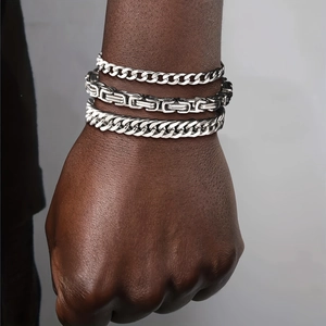 Close-up of three stacked silver hip hop chains on wrist including Cuban and Byzantine styles