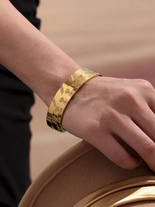 Detailed view of a gold geometric bangle with heart patterns and sparkling zircon stones