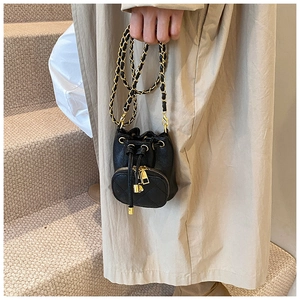 Detail of black quilted mini bucket bag with gold chain strap and drawstring closure