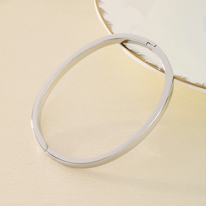 Detailed top view of a polished silver titanium steel bangle on a beige textured background
