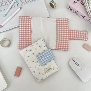Pink plaid and blue floral fabric book covers with plush details on a minimalist desk