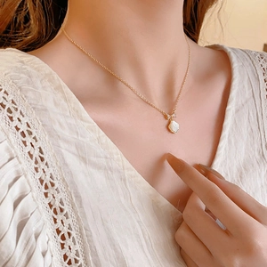 Gros plan du collier papillon plaqué or avec pendentif perle au cou d'une femme