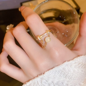 Detailansicht eines Goldrings mit Zirkonia, Kettentropfen und rundem Anhänger-Design