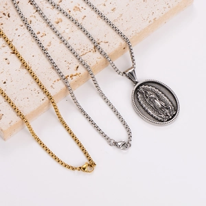 Guadalupe pendant necklaces in silver and gold steel resting on a stone block
