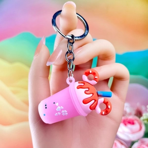 Pink ice cream milk tea cup keychain with donut detail held in a colorful setting