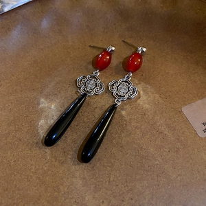 Close-up of vintage Chinese knot earrings with red bead and black teardrop pendant