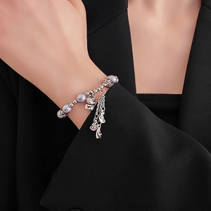 Dragon pearl bracelet with Fu character charm and silver tassels on black suit background
