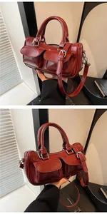 Detail of burgundy glossy leather handbag with double pockets and silver metal hardware