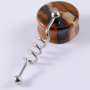 Macro detail of polished striped stone ear gauge with a silver metal spiral ring piercing
