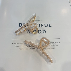 Detail view of pearl and rhinestone hair claw clips on an elegant magazine backdrop