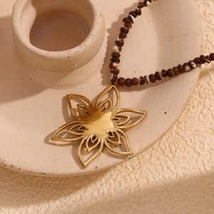Detail of 18K gold plated flower pendant necklace with natural brown shell beads on ceramic