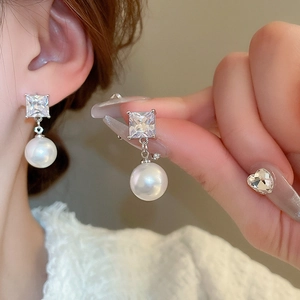 Close-up of model wearing square-cut crystal and white pearl drop earrings in silver finish