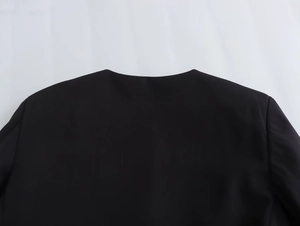 Detailed view of black round neckline and shoulder texture of casual short jacket