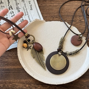 Close-up of ethnic leather necklace with metal feather and star charms on wood