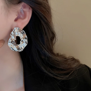 Detail of silver-toned irregular metal earrings with lava texture on a model side profile