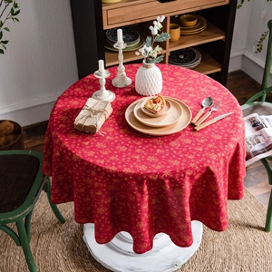 Festive red round Christmas tablecloth with gold snowflake patterns on a dining table