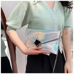 Dettaglio pochette argento effetto serpente con fibbia geometrica e tracolla dorata